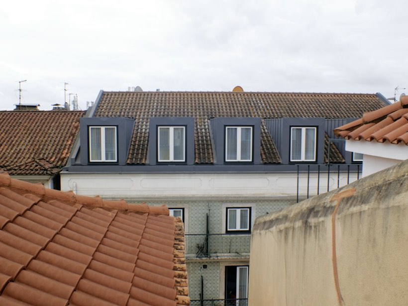Mehrfamilienhaus mit einer Reihe neuer Dachgauben über Ziegeldächern