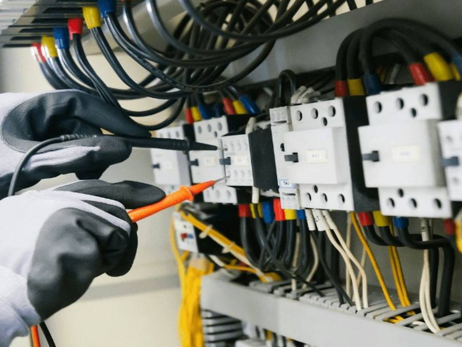 Prüfung von Schützen in einem Schaltschrank mit Prüfspitze und Schutzhandschuhen