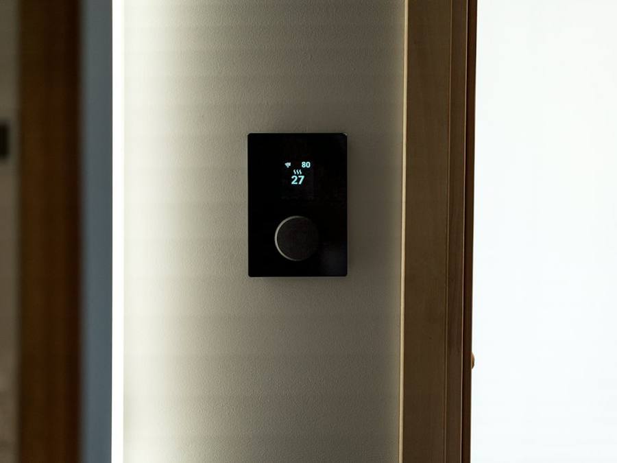 Schwarzes Smart-Home-Bedienpanel für die Raumtemperatur an einer hellen Wand