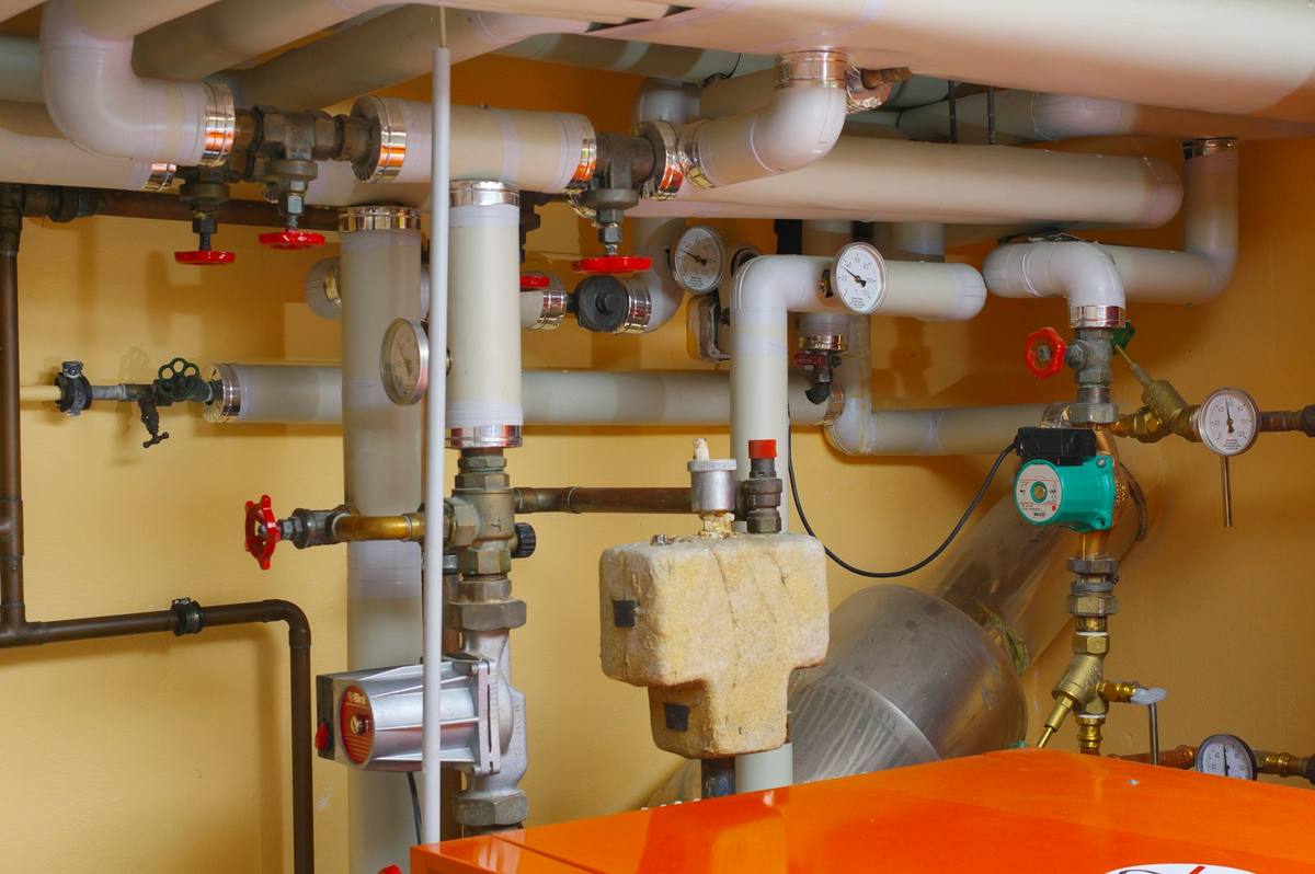 Modernisierter Heizungsraum mit gedämmten Rohrleitungen, Pumpen und Manometern