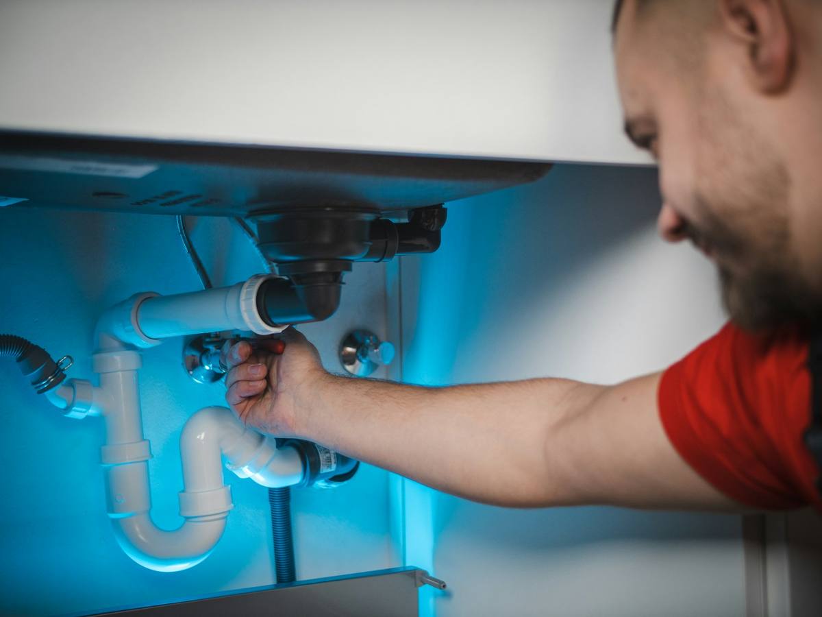 Installateur repariert den Siphon unter einem Waschbecken